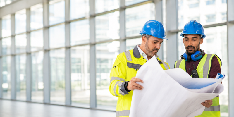 Workers at a construction site discussing the blueprint